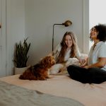 couple sitting in their bed with their pets