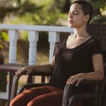 person sitting in a chair on a porch with their eyes closed