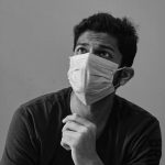 person wearing a protective face-mask looking into the distance