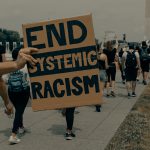 person holding an 'end systemic racism' sign at a protest in washington dc