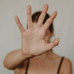 person holding their hand up to the camera to obscure their face